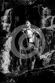 Profit business concept. businessman undressing at waterfall ready to swim. great finance waterfall. Wealth and success.