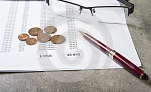 Profit and loss concept image of a pen, calculator and coins on financial documents