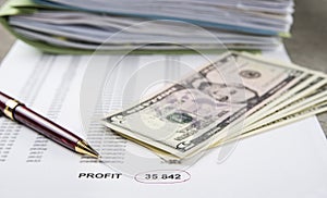 Profit and loss concept image of a pen, calculator and coins on financial documents