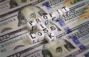 Profit or Loss, or Risk concept with letter cubes on a dollar bank notes.