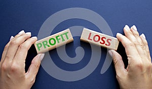 Profit or Loss symbol. Concept word Profit or Loss on wooden blocks. Businessman hand. Beautiful deep blue background. Business