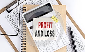 PROFIT AND LOSS word on sticky with clipboard and notebook, business concept