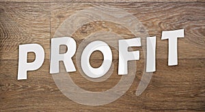 Profit text word letters cut from white paper on wooden background. Trade company profit and loss business concept