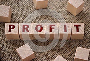 Profit text written on wooden block on burlap canvas background. Business profitability concept