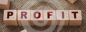 Profit text written on wooden block on burlap canvas background. Business profitability concept