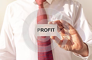 Profit word on business paper card held by a man in shirt and tie