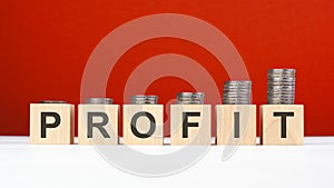 profit word made with wooden blocks with stacked coins. growing trend. red background. Investment growth concept