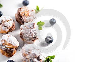 Profiterole or cream puff with filling, powdered sugar topping with berries, isolated on white background