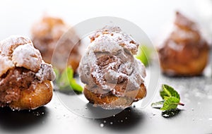 Profiterole or cream puff with filling, powdered sugar topping with berries, isolated on white background