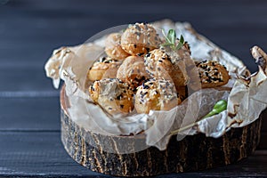 Profiteroles with pasta. On a wooden stand. Sprinkled with white and black sesame seeds. A microgreen of sunflower is decorated.