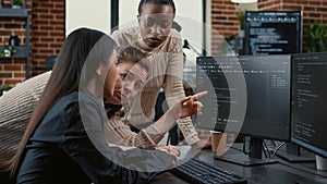 Programer pointing at computer screen explaining running code to coworkers brainstorming software ideas