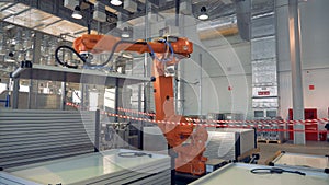Programmed machine carries white panels. Automated Robotic Arms Assembling innovative product.