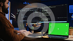 Programmer coding on computer next to isolated screen laptop in home office