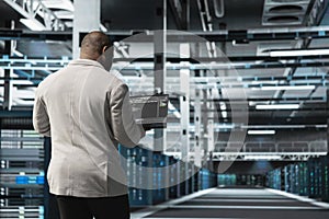 Programmer in data center typing on laptop, writing lines of code