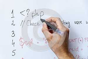 Programmer education and web development - hand with marker writing php programming code on whiteboard