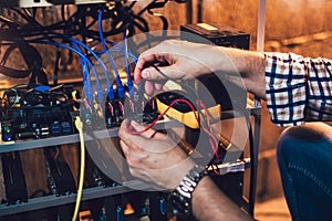 Programmer holding a wattmeter measuring cryptocurrency mining rig