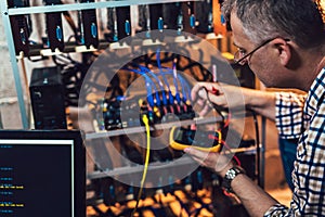 Programmer holding a wattmeter measuring cryptocurrency mining rig