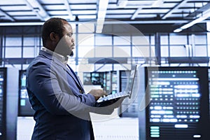 Programmer using laptop in data center with advanced technology