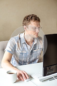 Programmer working from home, remote, home office. A man with glasses looks at the monitor. Remote work concept