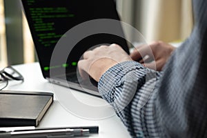Programmer working on laptop at office. Focus on programming code