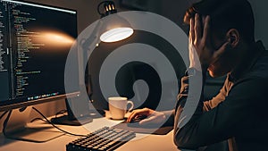 Programmer working late at night, stressed and tired, coding on computer