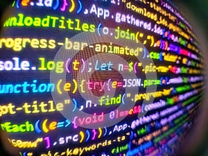 Programmer workplace. Digital binary data on computer screen. Abstract source code background. Programming code on black