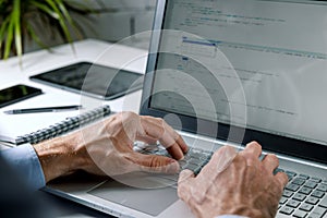 Programmer writing code on laptop computer in office. website programming, software development