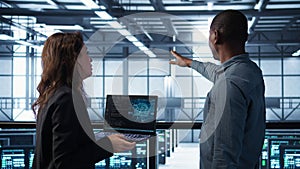 Programmers coding on laptop using artificial intelligence in server farm