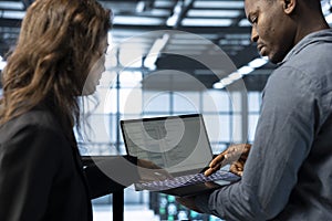 Programmers coding on notebook, adjusting server farm configurations