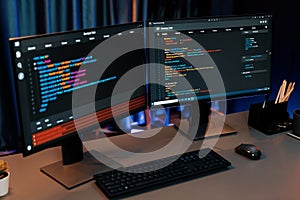 Programming code on computer two screen on desktop at neon light room. Infobahn.