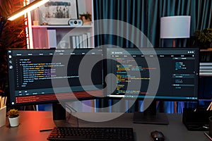 Programming code on computer two screen on desktop at neon light room. Infobahn.