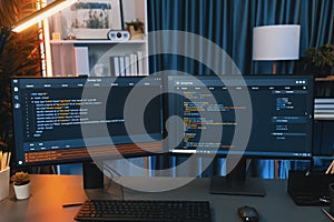 Programming code on computer two screen on desktop at neon light room. Infobahn.