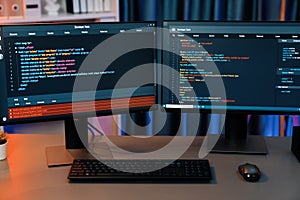 Programming code on computer two screen on desktop at neon light room. Infobahn.