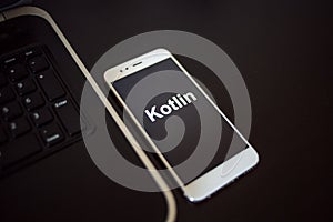 Programming language Kotlin for mobile development, concept. Smartphone near the laptop