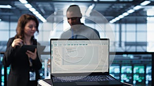 Programming language on notebook used by server room IT experts, close up