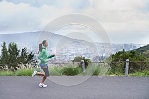 She progresses in her fitness everyday. A young woman sprinting along a mountain road on a crisp morning.