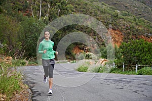 She progresses in her fitness everyday. A young woman sprinting along a mountain road on a crisp morning.