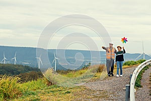 Progressive engineer with his son holding windmill toy in the mountain.