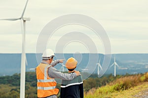 Progressive engineer with his son in the wind farm atop of the mountain.