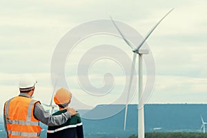 Progressive engineer with his son in the wind farm atop of the mountain.