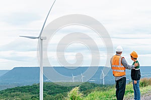 Progressive engineer with his son in the wind farm atop of the mountain.