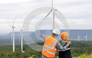 Progressive engineer with his son in the wind farm atop of the mountain.