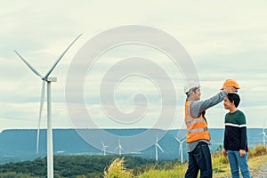 Progressive engineer with his son in the wind farm atop of the mountain.