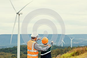 Progressive engineer with his son in the wind farm atop of the mountain.