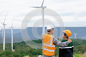 Progressive engineer with his son in the wind farm atop of the mountain.