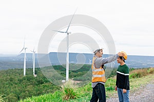 Progressive engineer with his son in the wind farm atop of the mountain.