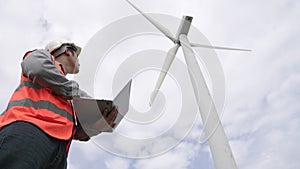Progressive engineer working with the wind turbine, with the sky as background.