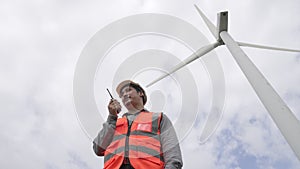 Progressive engineer working with the wind turbine, with the sky as background.