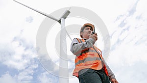 Progressive engineer working with the wind turbine, with the sky as background.