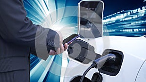 Progressive man charge electric car with technology background of binary code.